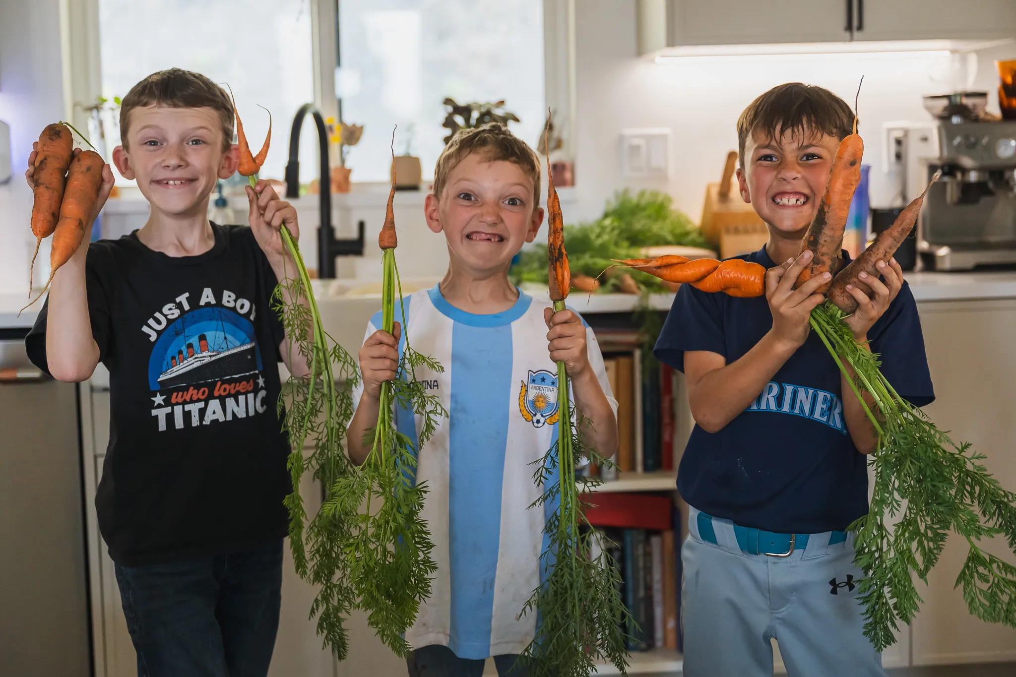 Three kids holding up carrots they grew